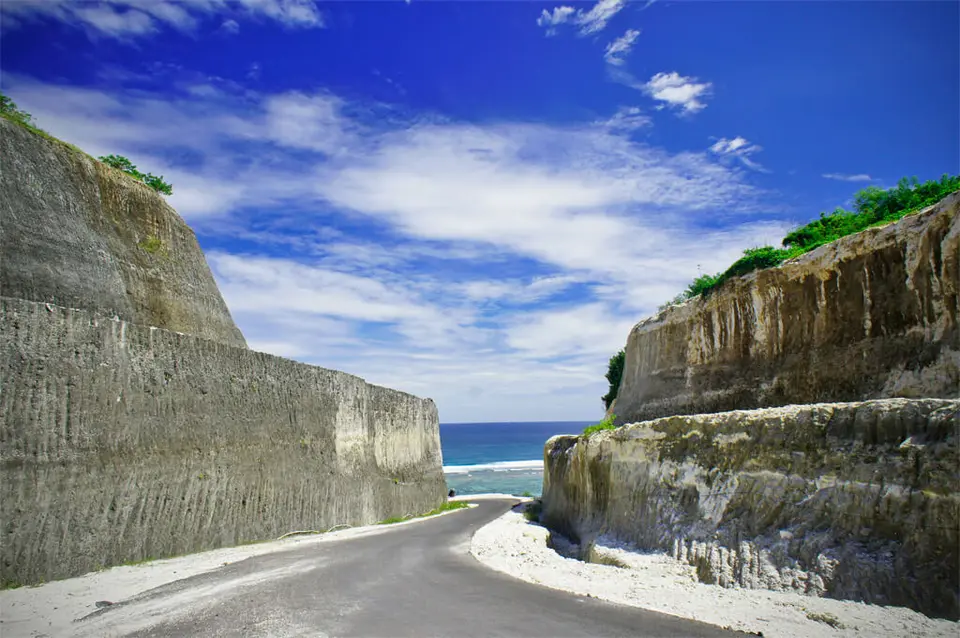 Road between tall limestone cliffs leading towards Pandawa Beach in Bali