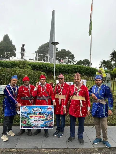 Travellers holding an Easy Way Holidays banner beside a garden monument