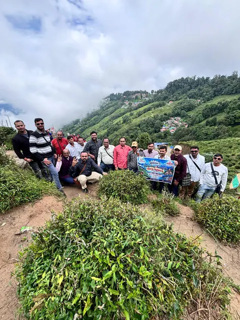 Tour group gathered on a hillside path surrounded by green mountains