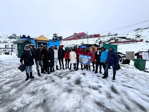 Group holiday photo on snow-covered ground with mountain buildings behind